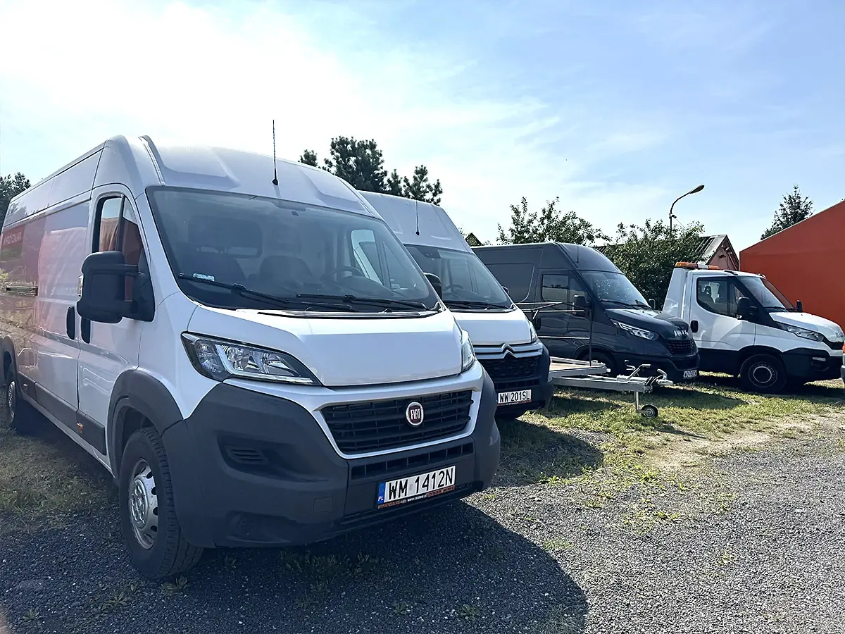 Biały Fiat Ducato na czele rzędu busów dostawczych
