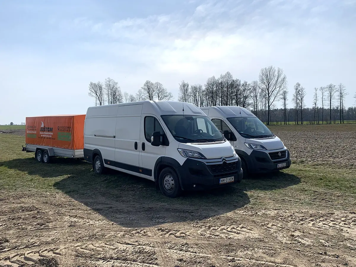 Busy dostawcze z przyczepą na skraju pola, widok z boku