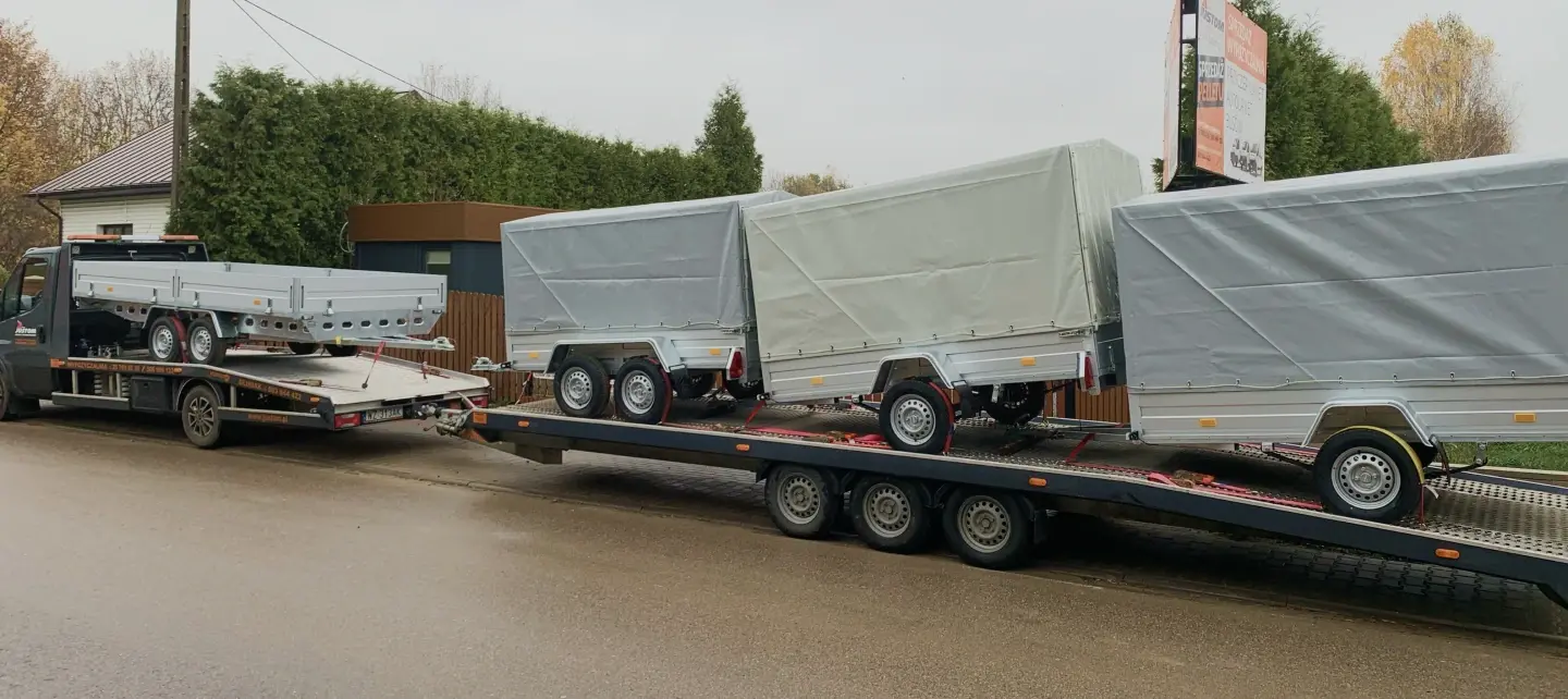 Kilka przyczep transportowych z plandeką załadowanych na lawecie