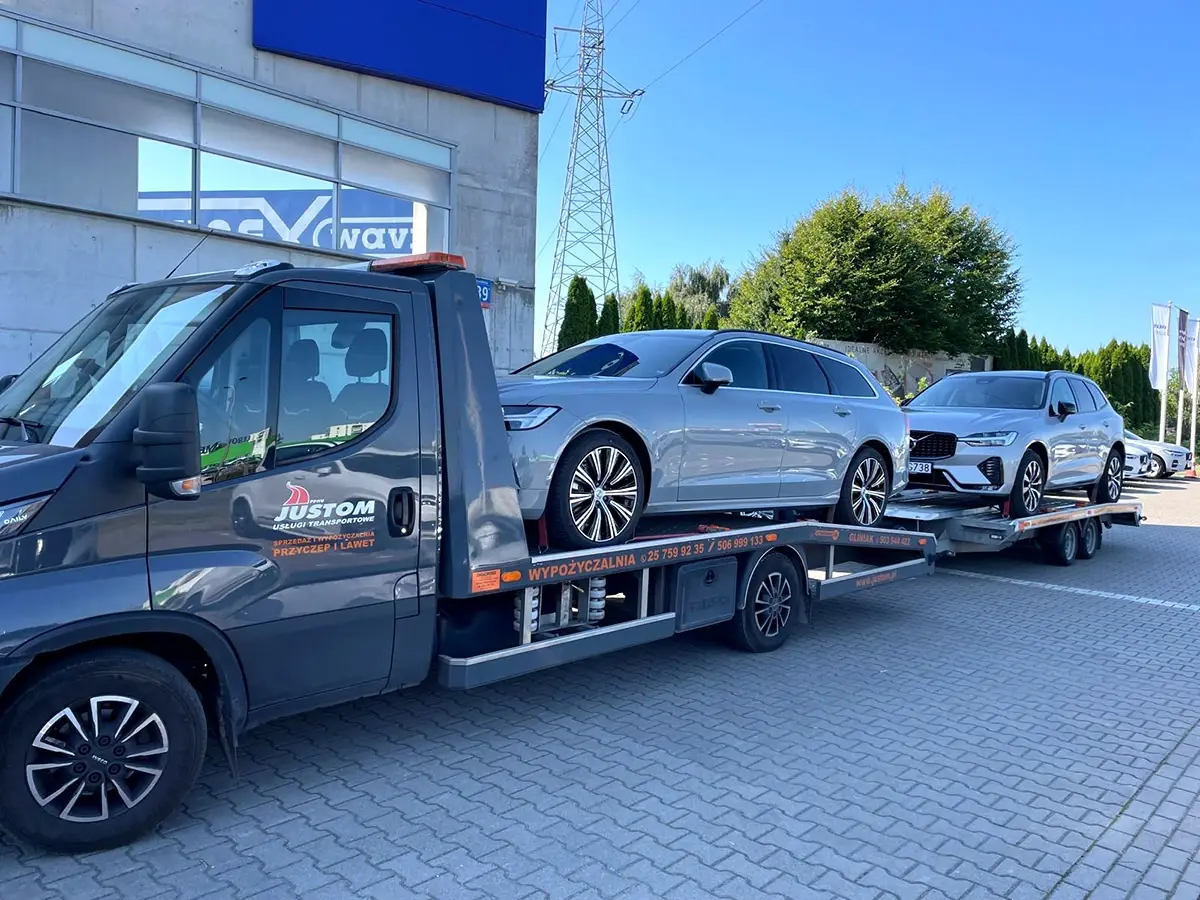 Srebrne Volvo na lawecie, kolejne samochody na przyczepie za nią
