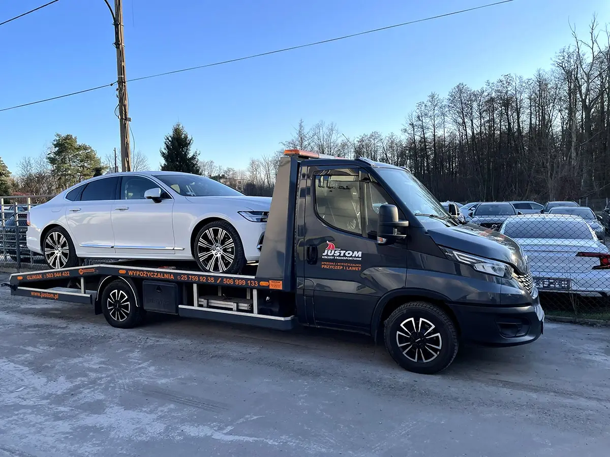 Biały sedan na lawecie Justom, zimą przy leśnej drodze